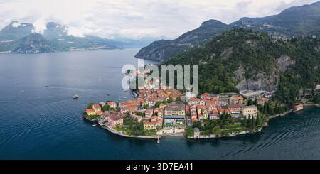 Vista aerea dei tetti di terracotta che scendono fino al lago scintillante, incorniciato da montagne verdeggianti, Varenna, Lombardia, Italia. Foto Stock