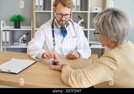 Medico che utilizza pulsossimetro per misurare la saturazione del sangue di una paziente anziana Foto Stock