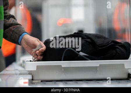 Baviera, Germania - 25 novembre 2025: Il bagaglio a mano è sottoposto a controlli di sicurezza obbligatori in aeroporto. Il personale controlla il processo mentre i sacchetti vengono scansionati sul nastro trasportatore per escludere gli oggetti pericolosi. Il giorno delle operazioni di prova per il nuovo gate del Terminal 1 dell'aeroporto di Monaco. *** Am Flughafen durchläuft das Handgepäck die obligatorische Sicherheitskontrolle. Personal überwacht den Ablauf, während Taschen auf dem Förderband durchleuchtet werden, um gefährliche Gegenstände auszuschließen. AM Tag des Probebetriebs für den neuen Flugsteig im Terminal 1 des Flughafens München. Foto Stock