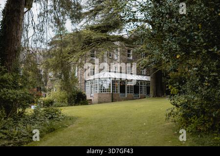 Una casa con un grande giardino e una serra. La casa è circondata da alberi e cespugli. Il giardino è rigoglioso e verde, e la serra è una meraviglia Foto Stock