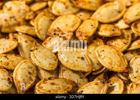 Semi di zucca piccanti e arrostiti fatti in casa in una ciotola con polvere di peperoncino Foto Stock