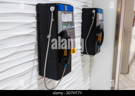 Due telefoni pubblici pendono su una moderna parete bianca testurizzata all'interno. Toronto, ON Foto Stock