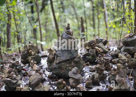 Calmo cairn di roccia zen che mostra equilibrio spirituale nella foresta verde. tranquilla pila di pietra che rappresenta armonia e serenità nella natura, meditativa all'aperto Foto Stock