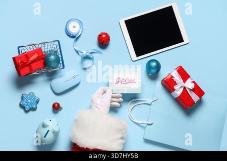 Babbo Natale con carta regalo, gadget moderni e decorazioni natalizie su sfondo colorato Foto Stock