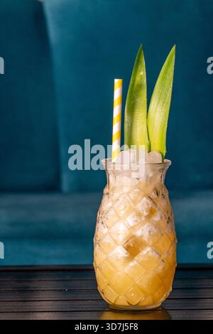 Cocktail di ananas in vetro a forma di ananas su un tavolo di legno in un bar Foto Stock