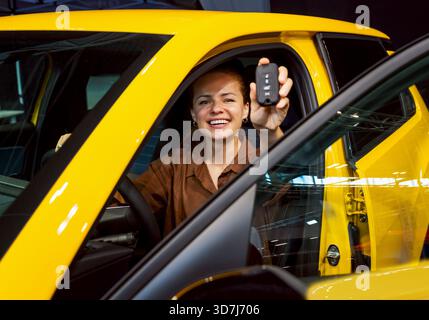 Cliente donna felice e la sua nuova vettura presso la concessionaria Foto Stock
