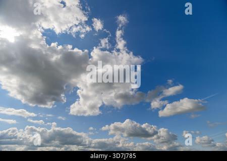 Una vista serena di soffici nuvole che si muovono in un cielo blu luminoso, perfetto per ispirarsi alla natura Foto Stock