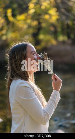 Donna che tiene un bouquet di lavanda sul viso, sorride e si gode il profumo della natura Foto Stock