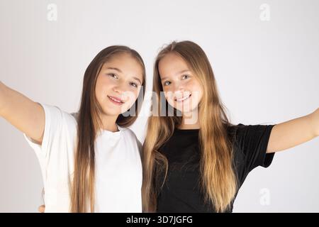le ragazze nell'immagine sorridono alla telecamera con le braccia estese verso l'esterno. Foto Stock