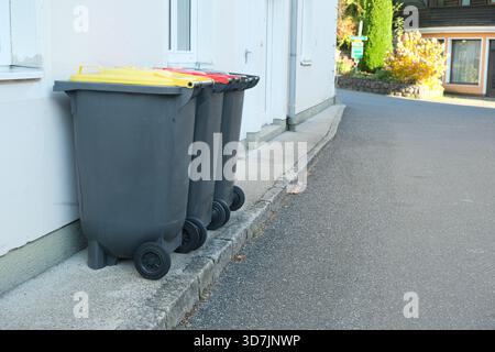 Smistamento dei rifiuti in Europa. Lattine per spazzatura con coperchi colorati per diversi tipi di spazzatura Foto Stock