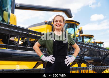 Lavoratrice agricola orgogliosa con trebbiatrici mietitrebbia a file Foto Stock