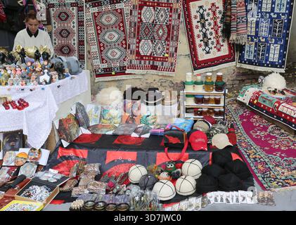 Tbilisi, Georgia-13 novembre 2025: Negoziante donna non identificata in piedi accanto a un tavolo e vendendo souvenir nel suo negozio di articoli da regalo Foto Stock