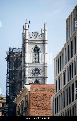 Montreal, Canada - 14 agosto 2025: Vista del centro con la torre in pietra della basilica di Notre-Dame e i moderni edifici circostanti Foto Stock