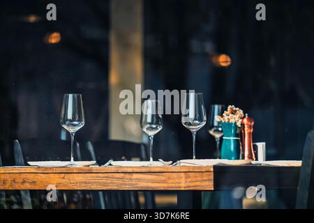 Un tavolo con quattro bicchieri da vino e uno shaker per sale e pepe. Il tavolo è pronto per un pasto Foto Stock