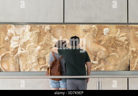 Un paio di turisti che guardano sezioni del fregio del Partenone, mostra dall'antica Grecia; Museo dell'Acropoli, Atene, Grecia; Foto Stock