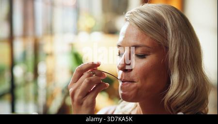 Casa, donna e mangiare con cucchiaio per colazione, pasto delizioso e soddisfazione del gusto per la salute. Persona affamata, gusta il cibo e i sapori nel soggiorno Foto Stock