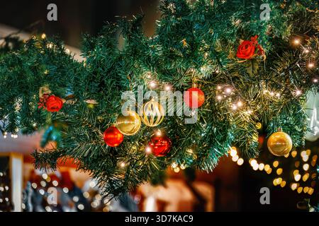 Primo piano di una vivace ghirlanda natalizia adornata da scintillanti baule rosse e dorate e da calde luci scintillanti. Foto Stock