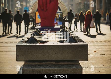 Erevan Armenia 11.20.2025. Un gruppo di persone passeggia davanti a una grande scultura rossa di una mano e a una fontana Foto Stock