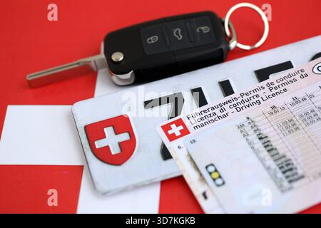 Targa Svizzera e chiave di accensione sulla bandiera svizzera primo piano. Patente di guida e concetto di immatricolazione Foto Stock