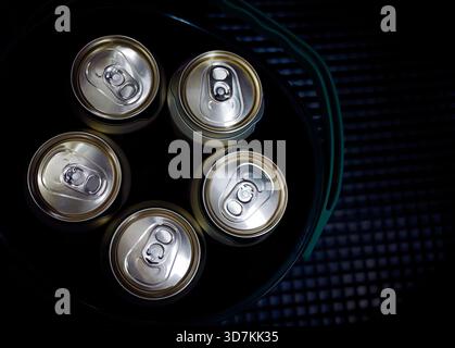 Concetto di ristoro. Stesa piatta di lattine metalliche chiuse contenenti birra, bibite gassate o bevande gassate all'interno di un cestello di plastica. Linguetta ad anello lucido det Foto Stock