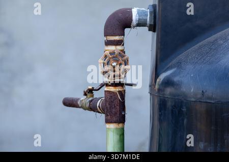 Primo piano di un complesso sistema di alimentazione dell'acqua in una casa in Bangladesh: Tubo in metallo arrugginito con manopola della valvola a saracinesca, valvole a sfera con impugnatura a leva, tutte collegate a. Foto Stock