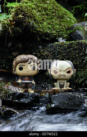 Funko Pop action figure di Frodo e Gollum dal film il Signore degli anelli. Pietre umide mossy, acqua di ruscello schiumosa. Foto Stock