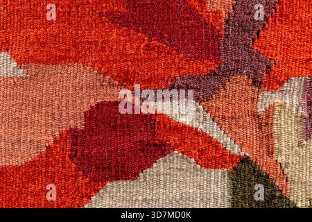 Primo piano in tessuto rosso arancio caldo, motivo geometrico astratto dal tappeto vintage kilim, fibre di filati di lana sfondo macro dettagliato Foto Stock