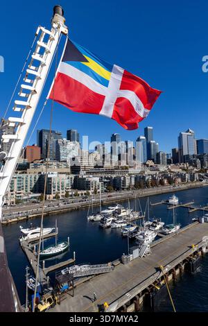 Lo skyline del centro cittadino di Seattle è visibile dal lungomare del Pier 66 con la bandiera rossa civile delle Bahamas in primo piano: Seattle, Washington, USA Foto Stock