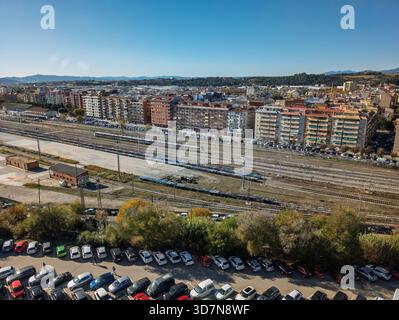 Vista aerea della città con edifici residenziali, binari ferroviari multipli, un treno e parcheggi popolati Foto Stock