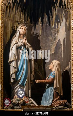 Cherasco, Italia - 10-20-2025: Statua (XIX secolo) dell'apparizione di nostra Signora di Lourdes a Bernadette Soubirous. Foto Stock