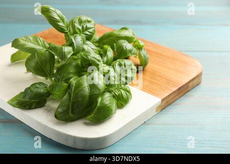 Foglie di basilico fresco su un tavolo di legno azzurro, primo piano Foto Stock