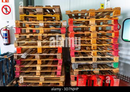 Pila di pallet in legno lasciati in magazzino logistico per la preparazione degli ordini. Foto Stock
