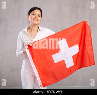 Giovane donna in posa in studio con bandiera svizzera Foto Stock