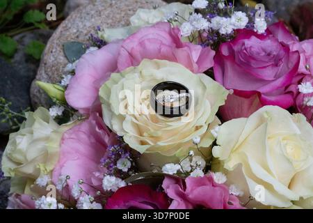 Anelli nuziali su un bouquet floreale Foto Stock