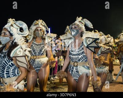 Donne che indossano intricati costumi animalistici con corna di montone, piume e maschere facciali sfilano durante il carnevale di Sitges di notte in Catalogna, Spagna Foto Stock