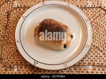 Croissant al cioccolato appena sfornato su piatto e Placemat. Foto Stock