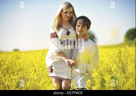 Coppia in abito tradizionale a fiori gialli campo Foto Stock