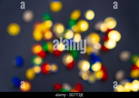 Una dispersione di miniature colorate (pulsanti) in rosso, blu, verde e beige su una superficie nera, con una profondità di campo bassa. Foto Stock