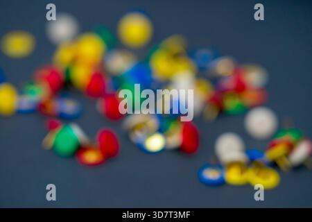 Una dispersione di miniature colorate (pulsanti) in rosso, blu, verde e beige su una superficie nera, con una profondità di campo bassa. Foto Stock