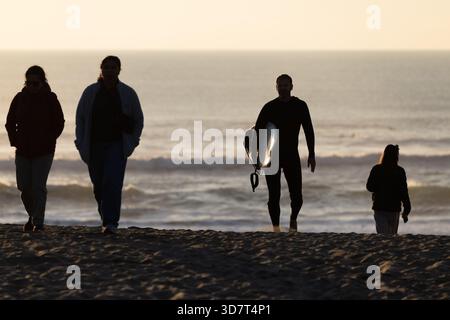 Sagome di amanti della spiaggia e surfisti al tramonto su Ocean Beach Foto Stock