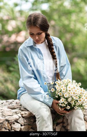 Donna Fiori Margherita: La ragazza tiene il bouquet nel parco, in estate, in regalo o in un piacevole momento all'aperto. Foto Stock
