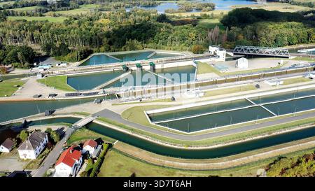 Vista aerea di un complesso sistema di chiuse per canali che facilita il traffico marittimo e marittimo, circondato da lussureggianti alberi e campi verdi Foto Stock