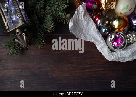 Composizione natalizia con ornamenti in vetro vintage, rami di pino, lanterna e fiocco di neve all'uncinetto fatto a mano su sfondo di legno scuro. Foto Stock