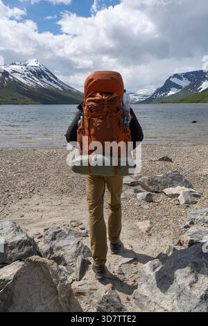 Escursionista con zaino pesante che cammina verso il lago Gjevilvatnet, Norvegia Foto Stock