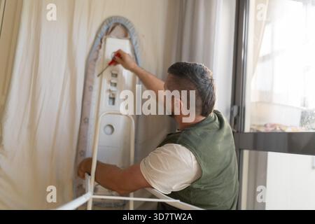 Uomo che ripara appendiabiti con un cacciavite Foto Stock