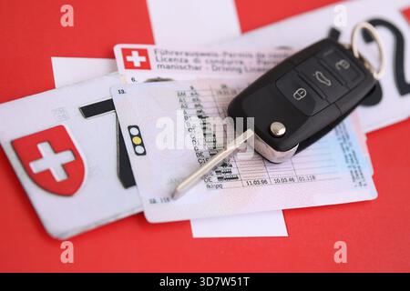 Targa Svizzera e chiave di accensione sulla bandiera svizzera primo piano. Patente di guida e concetto di immatricolazione Foto Stock