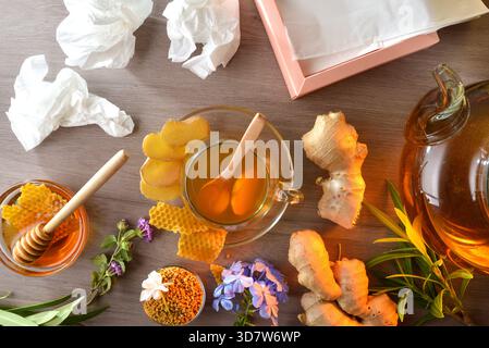 Infusione naturale a base di radice di zenzero e miele in una tazza di vetro come buon rimedio domestico per raffreddori e congestione su un tavolo di legno con tessuti usati e. Foto Stock
