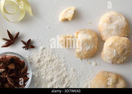 Dettagli macro di biscotti all'anice fatti in casa con zucchero su un tavolo bianco con ingredienti e farina sparsi per le celebrazioni. Vista dall'alto. Foto Stock