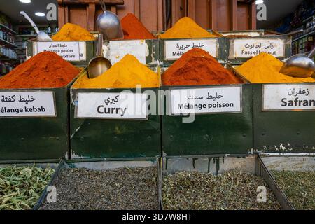 Varie spezie colorate in contenitori etichettati presso un mercato delle spezie. Marrakech, Marocco Foto Stock