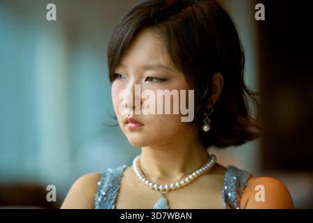 Una giovane donna con taglio di capelli e accessori perlati guarda con attenzione il lato. Shanghai, Cina Foto Stock